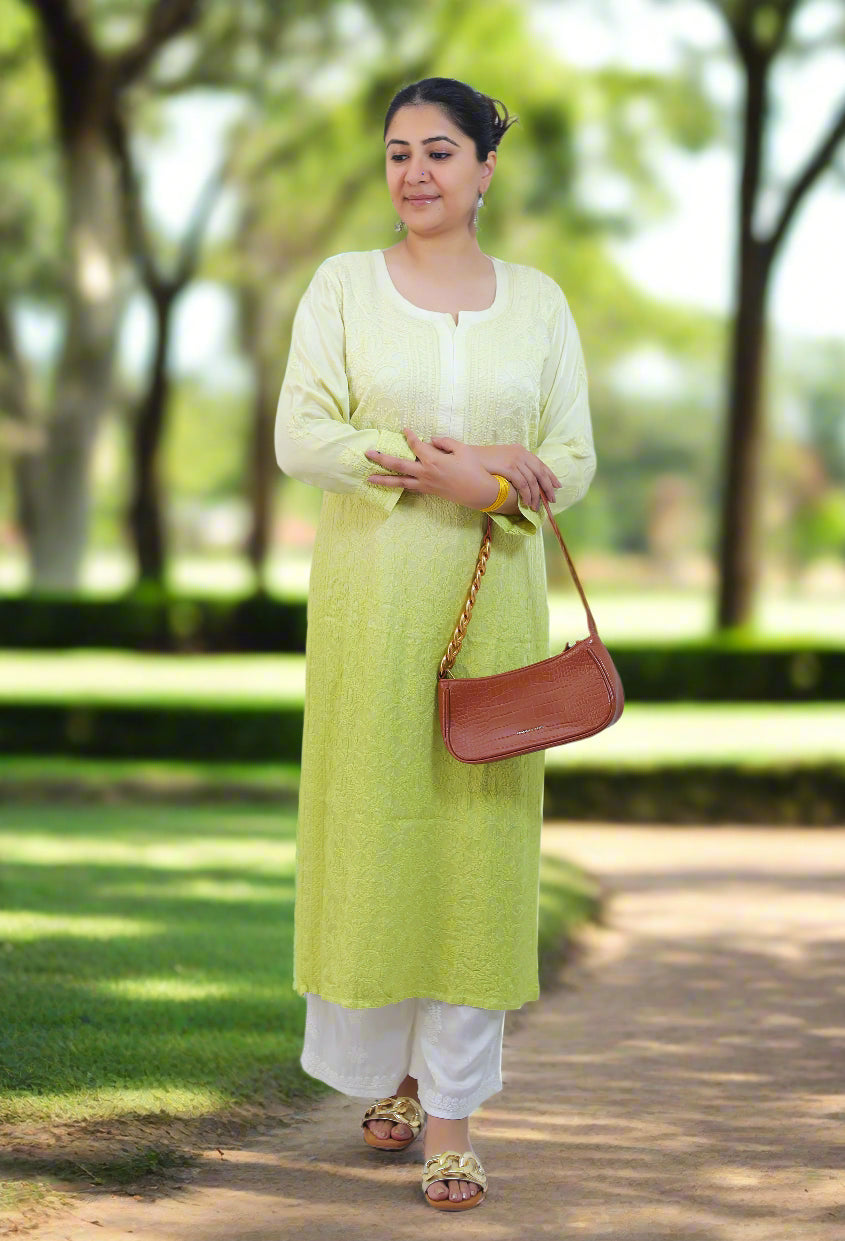 Woman wearing a light green kurta with white pants, holding a brown handbag on a white background