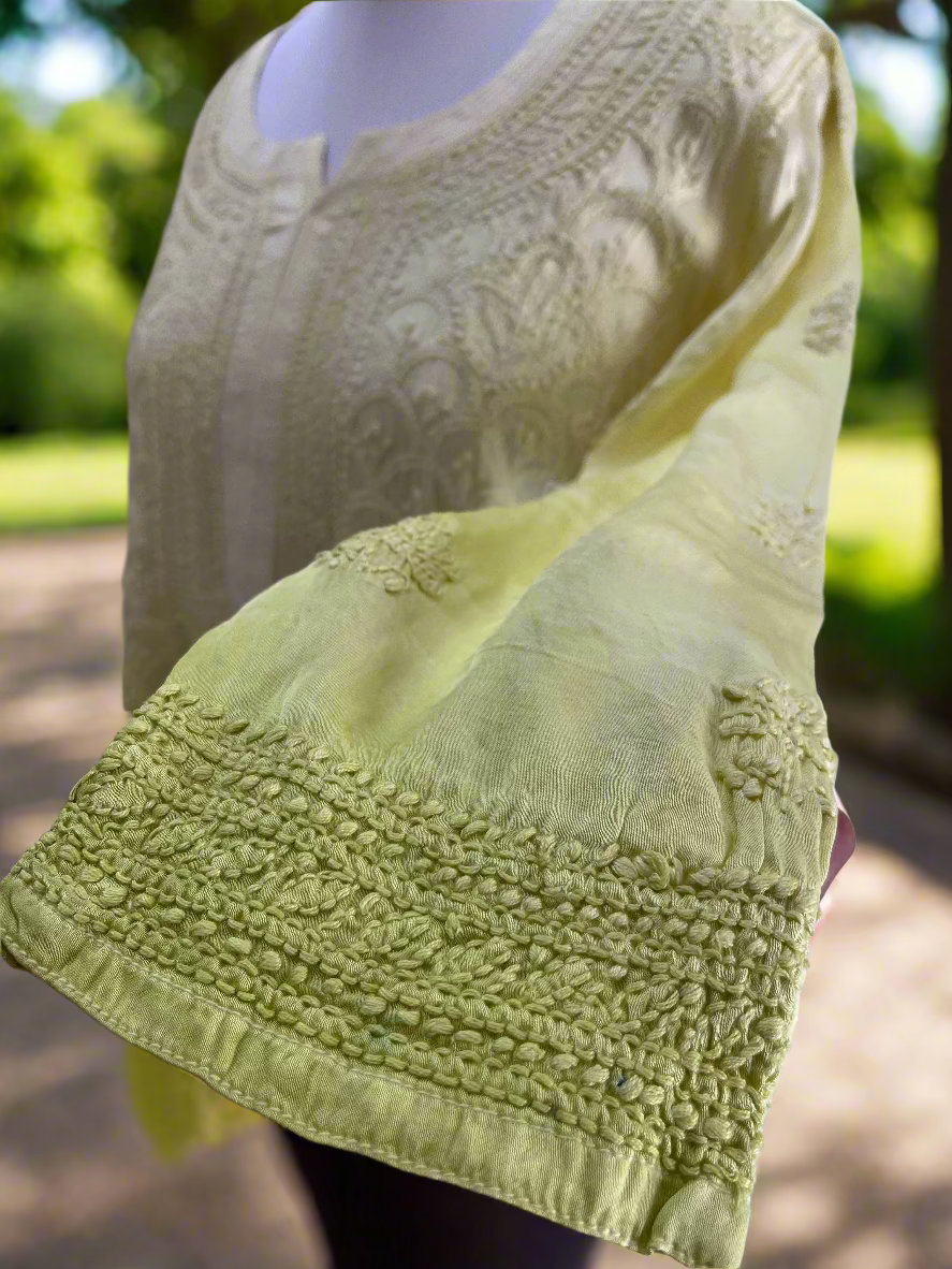 Light green fabric with intricate patterns held by a hand against a neutral background