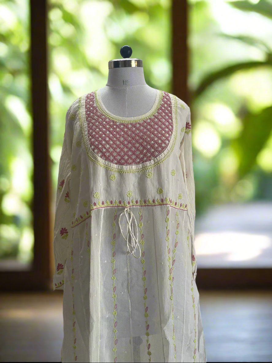 Mannequin wearing a long, sheer dress with floral embroidery on a plain background