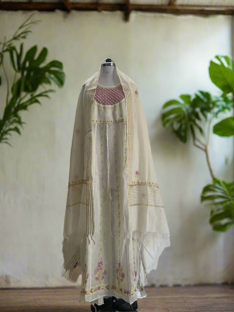 Mannequin wearing a long, light-colored embroidered dress against a plain background