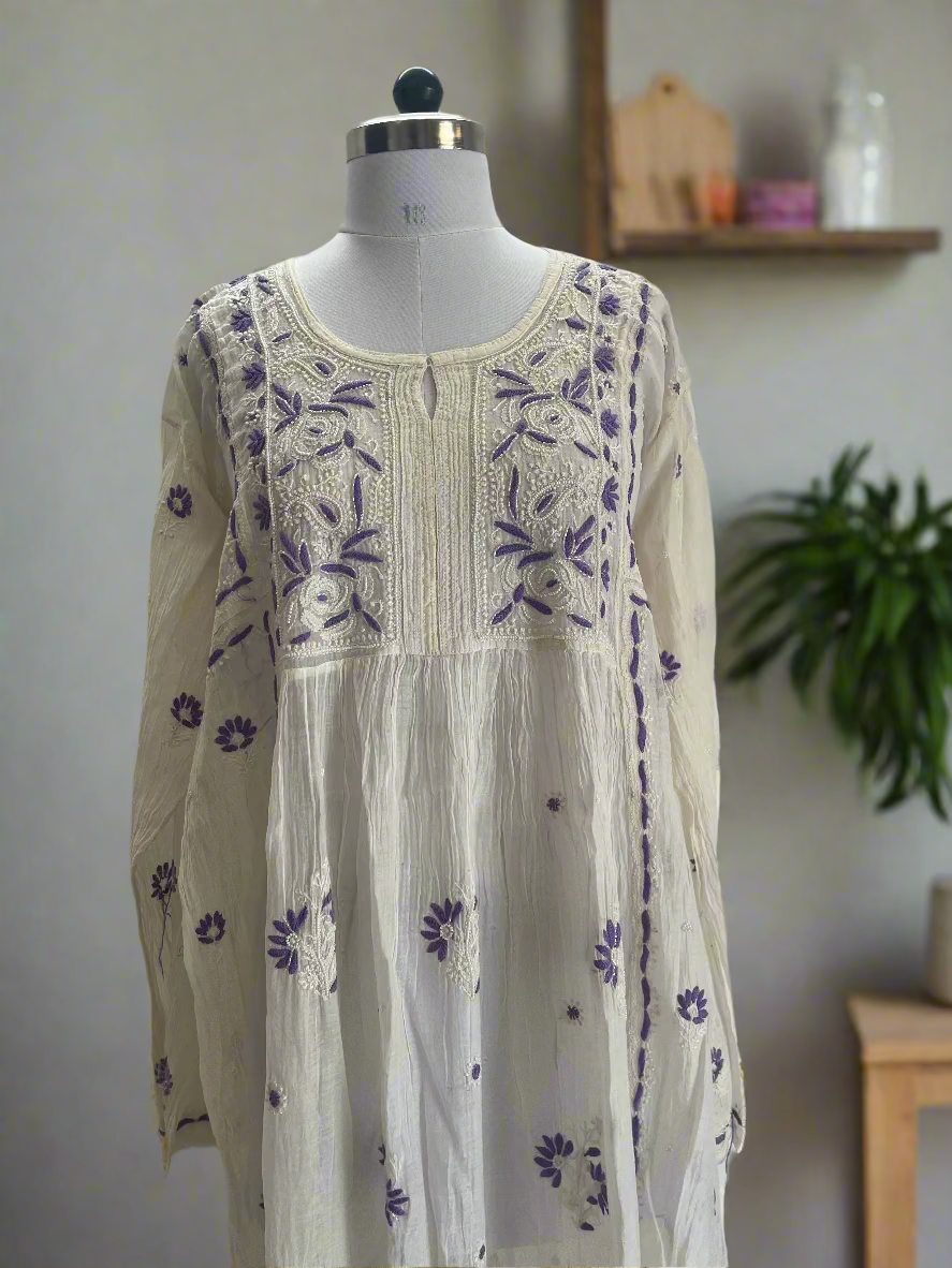 White dress with purple floral embroidery on a mannequin against a plain background