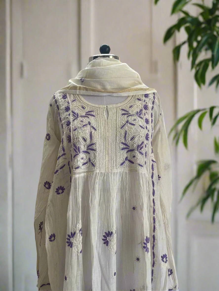 White embroidered dress with purple patterns on a mannequin against a plain background
