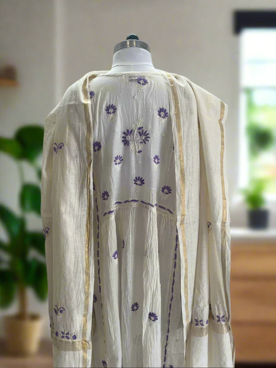 White dress with purple floral patterns on a mannequin against a plain background