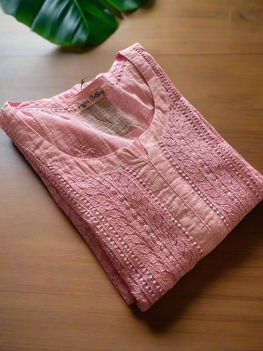 Pink quilted baby jacket on a floral-patterned bedspread