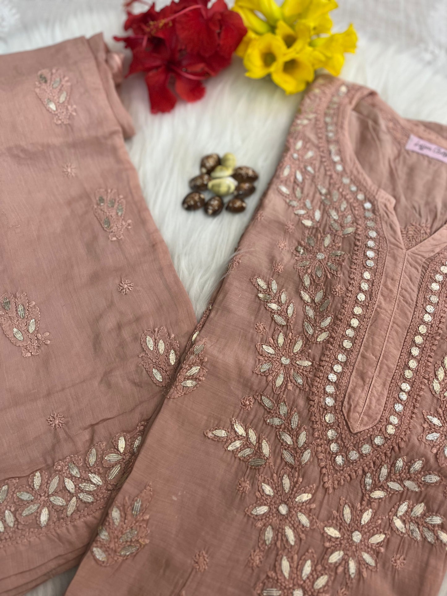 Brown embroidered outfit with floral decorations on a white background