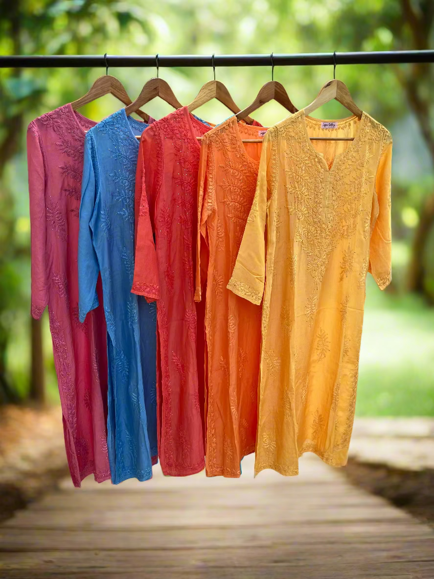 Five colorful dresses hanging on a rack outdoors.