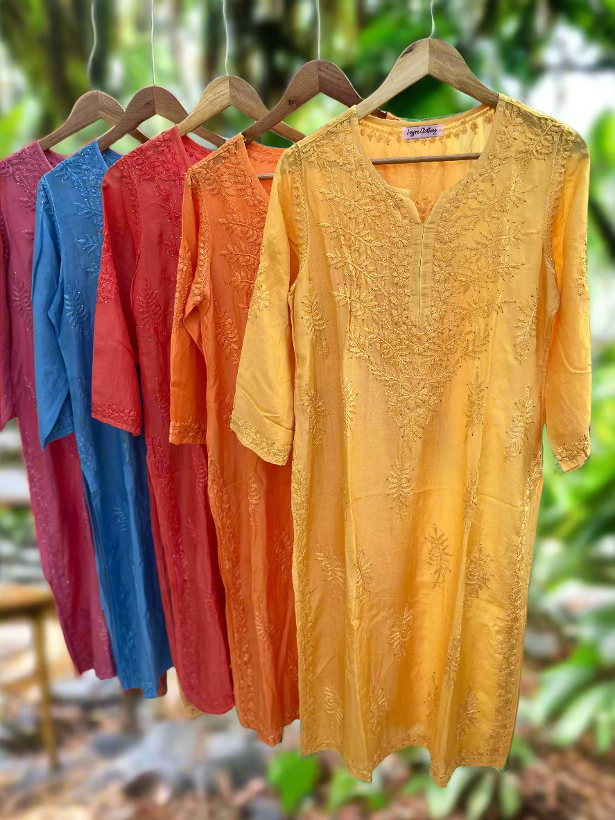 Colorful embroidered shirts on hangers against a neutral background