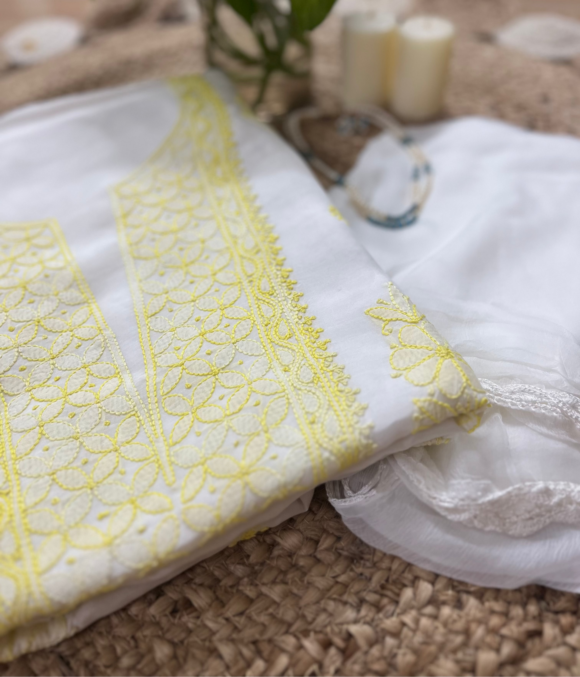 Close-up of a white fabric with yellow lace detailing on a textured surface.