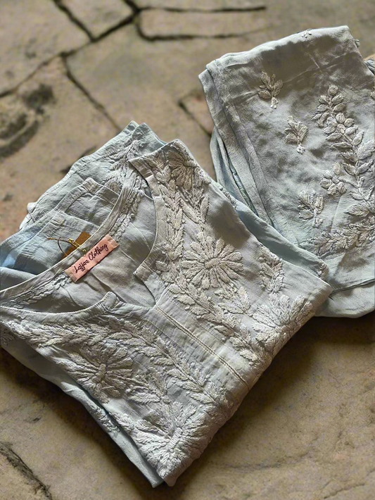 Folded light gray embroidered shirt on a floral-patterned surface