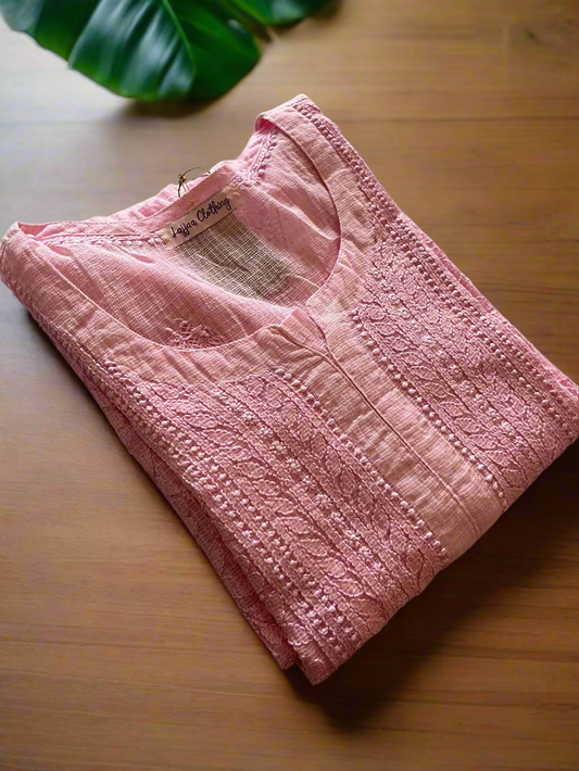 Pink quilted baby jacket on a floral-patterned bedspread
