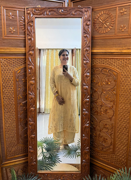 Person taking a mirror selfie in front of a large wooden carved screen.